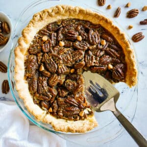 pie server resting in a pan of pecan pie.
