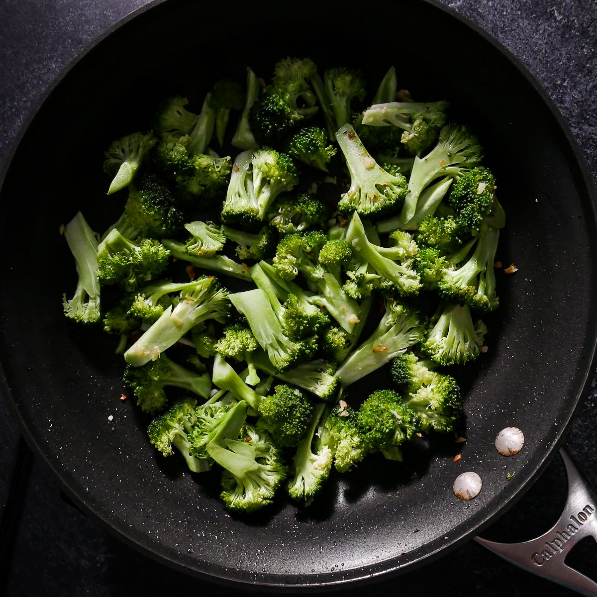 cooking-broccoli.jpg Prepped broccoli being cooked in a large skillet.