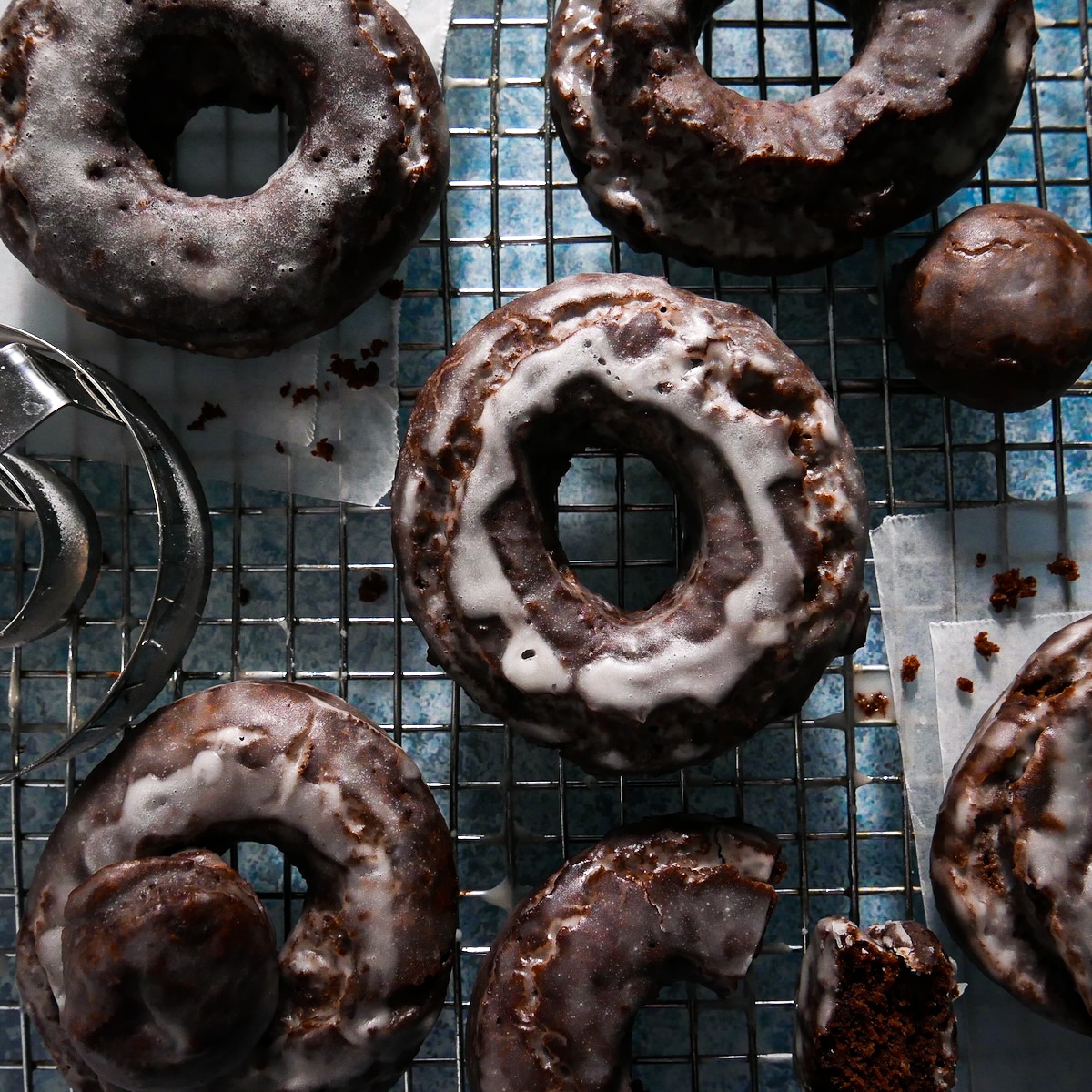Fried and glazed donuts cooling on a wire rack.