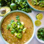 bowl of white veggie chili garnished with fresh cilantro, avocado, and sliced jalapenos.
