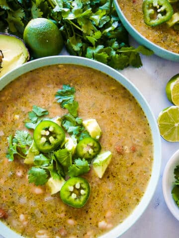 bowl of white veggie chili garnished with fresh cilantro, avocado, and sliced jalapenos.