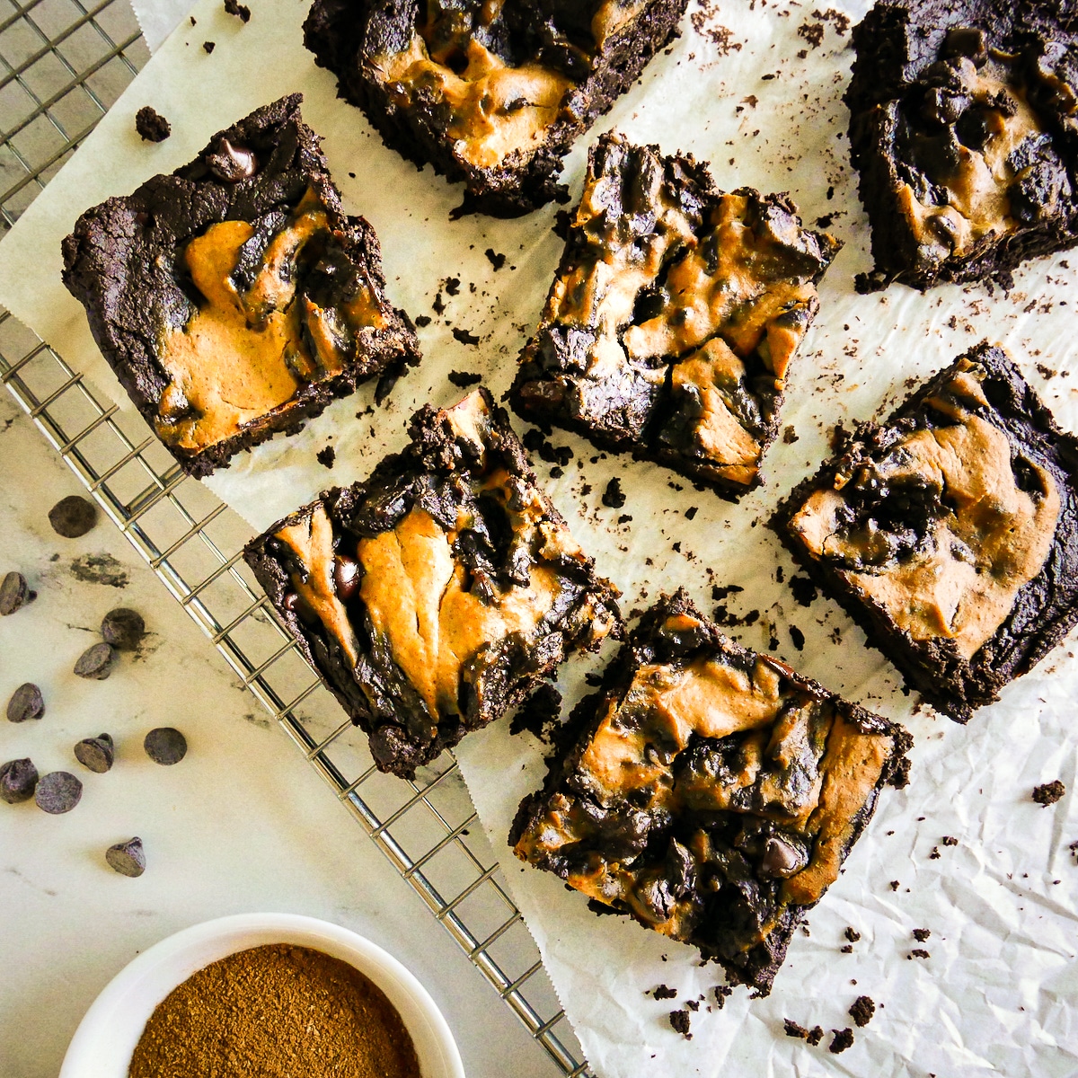 Eggless pumpkin brownies on a cooling rack with crumbs.