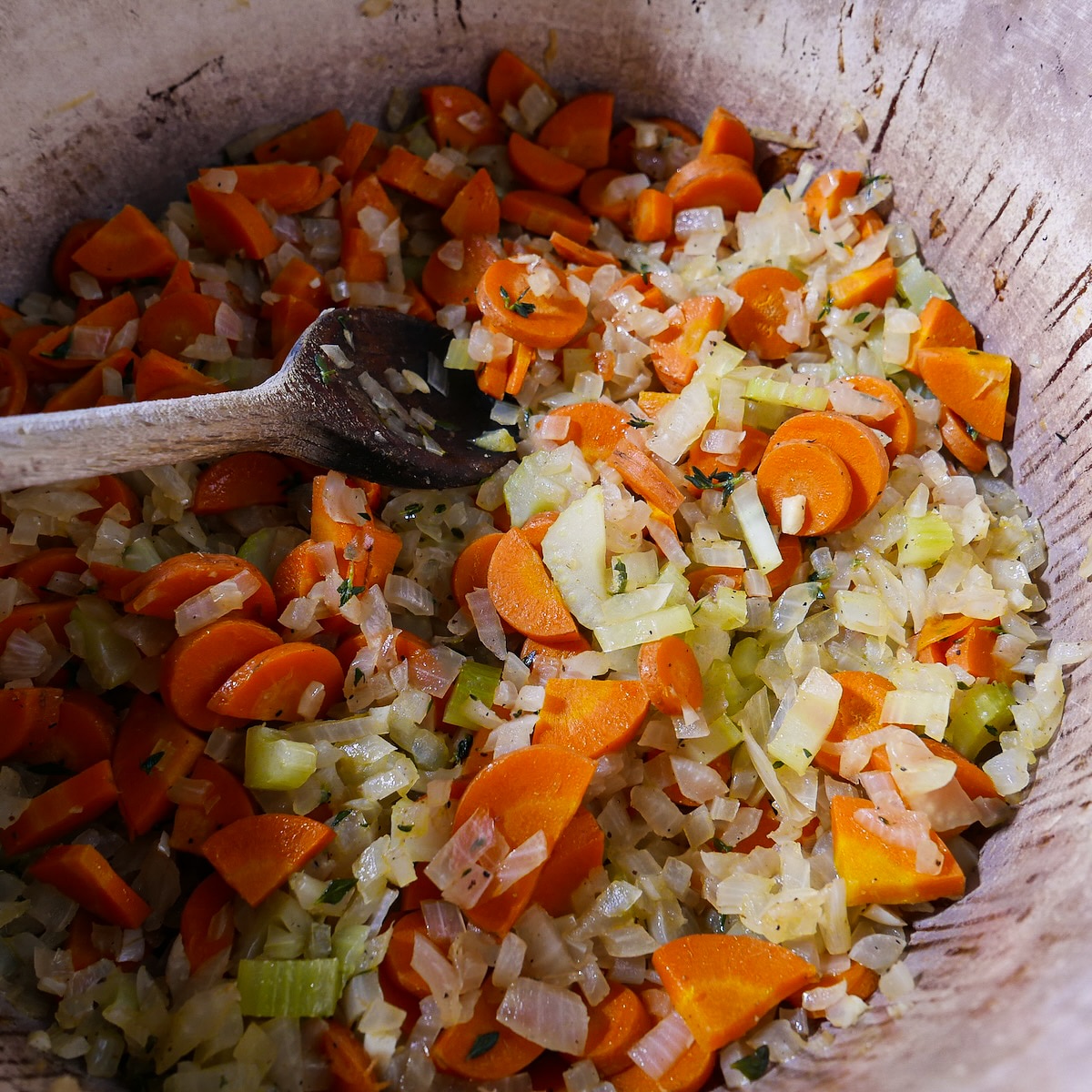 Onion, celery, carrots, garlic, and seasonings cooking in a larg pot.
