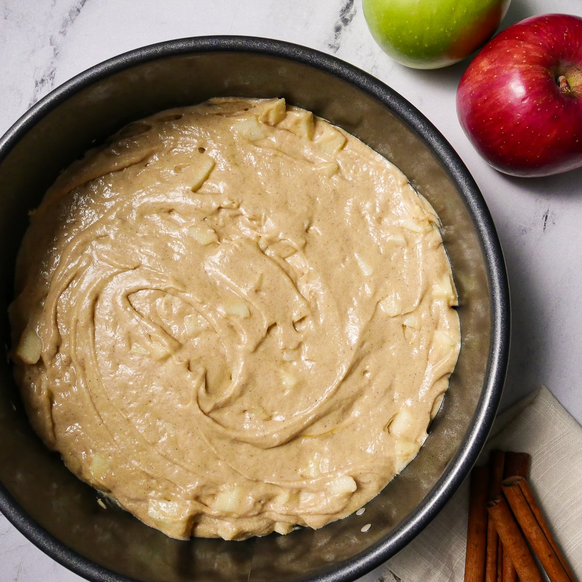 Apples mixed into cake batter and poured into a prepared springform pan.