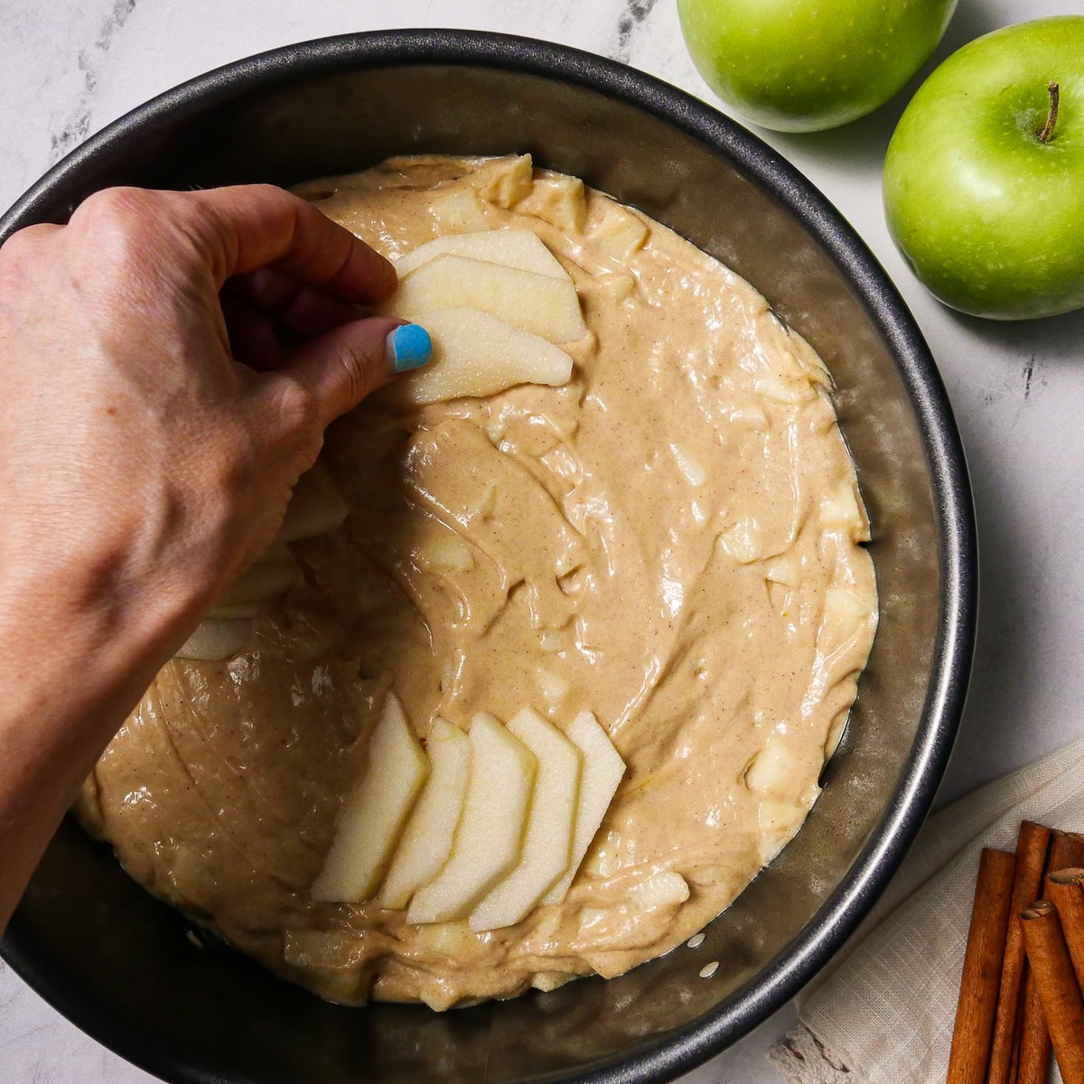 Apple slices arranged on top of cake batter in a springform pan.