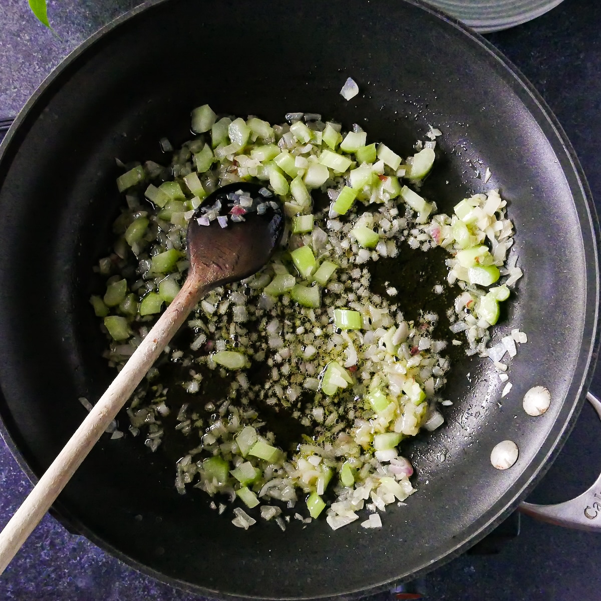 Celery and shallots cooking in a skillet.