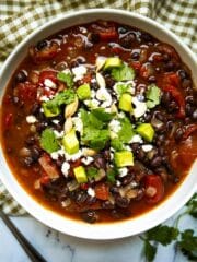 bowl of vegetarian black bean soup garnished with cilantro and avocado.