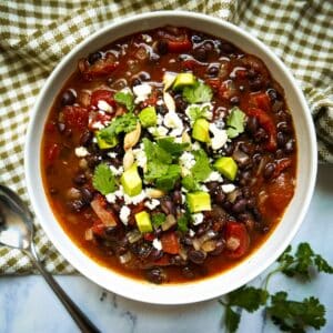 bowl of vegetarian black bean soup garnished with cilantro and avocado.