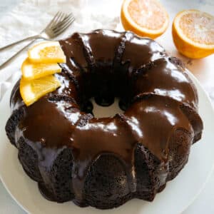 chocolate orange cake garnished with slices of orange and resting on a platter.