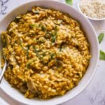bowl of vegan risotto with a spoon, white napkin, and sage leaves.
