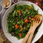 Roasted squash salad in a bowl with arugua, Parmesan cheese, and pecans.