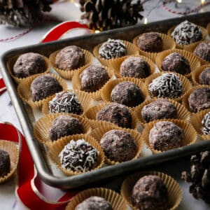 Traditional rum balls arranged in paper liners on a tray.