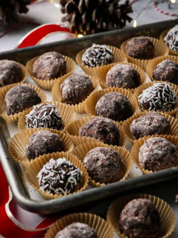 Traditional rum balls arranged in paper liners on a tray.