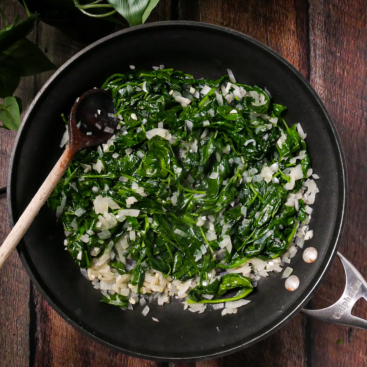 Wilted spinach added to skillet.