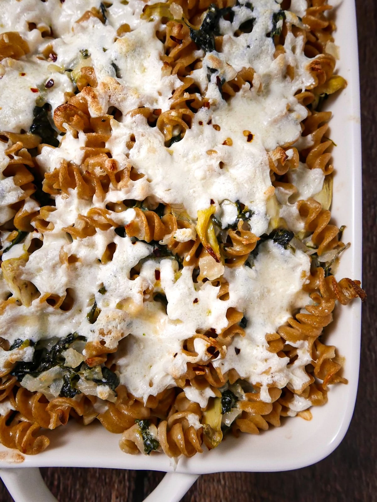Baked spinach artichoke pasta in a baking dish.