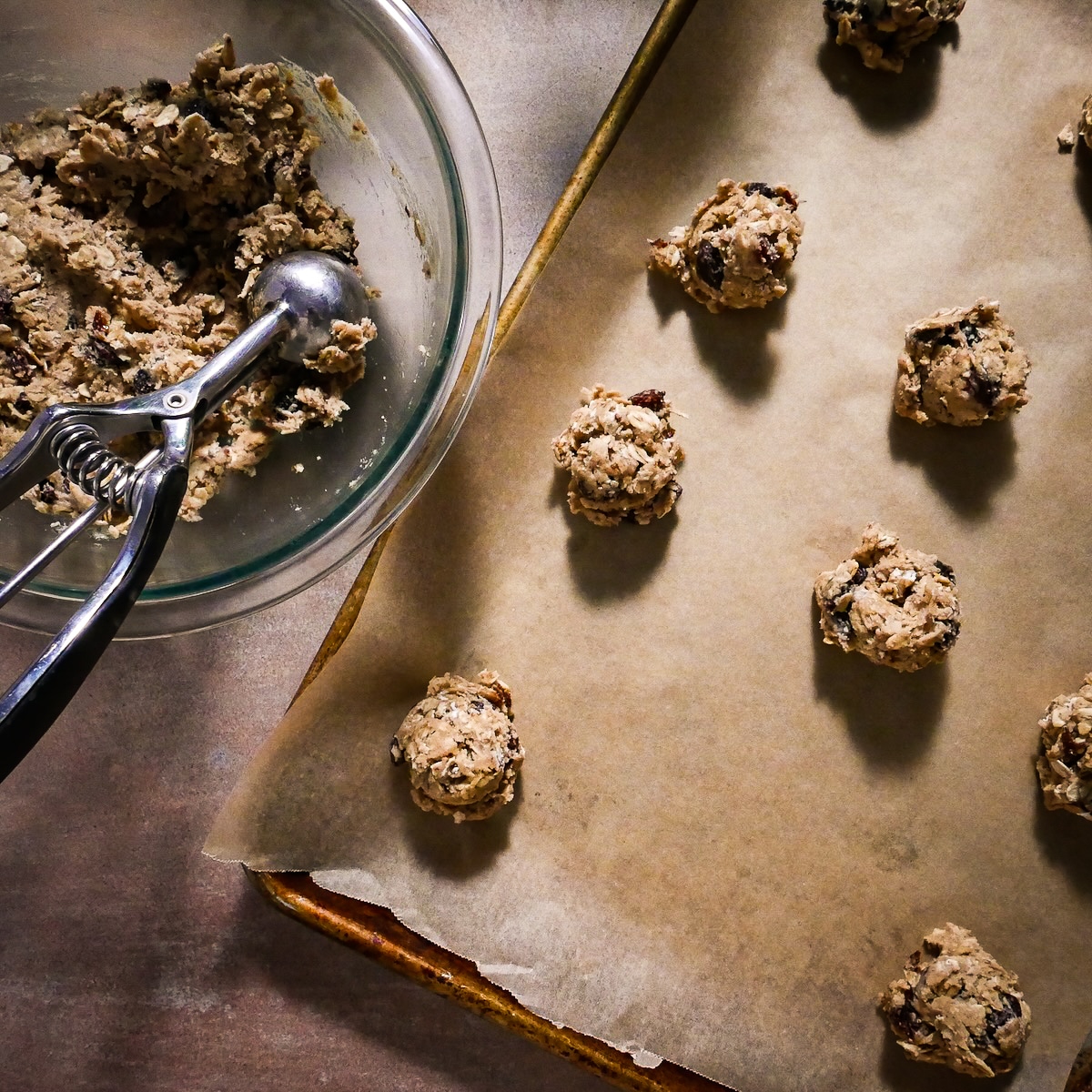 Scooping cookie dough onto lined baking sheet.
