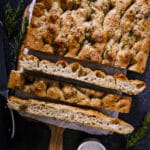 Golden sourdough focaccia sliced into squares on parchment paper.