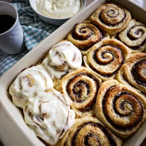 pan of fluffy cinnamon rolls with cup of coffee on the side.