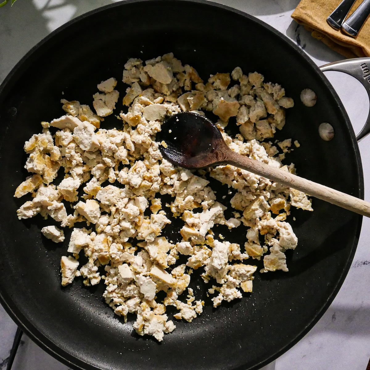 Lightly browned tofu being cooked in a frying pan. 