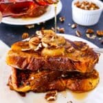 Rich french toast with caramelized bananas and syrup being poured on top.