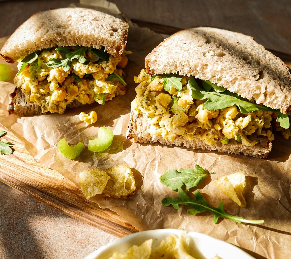 Smashed chickpea sandwich assembled on parchment.