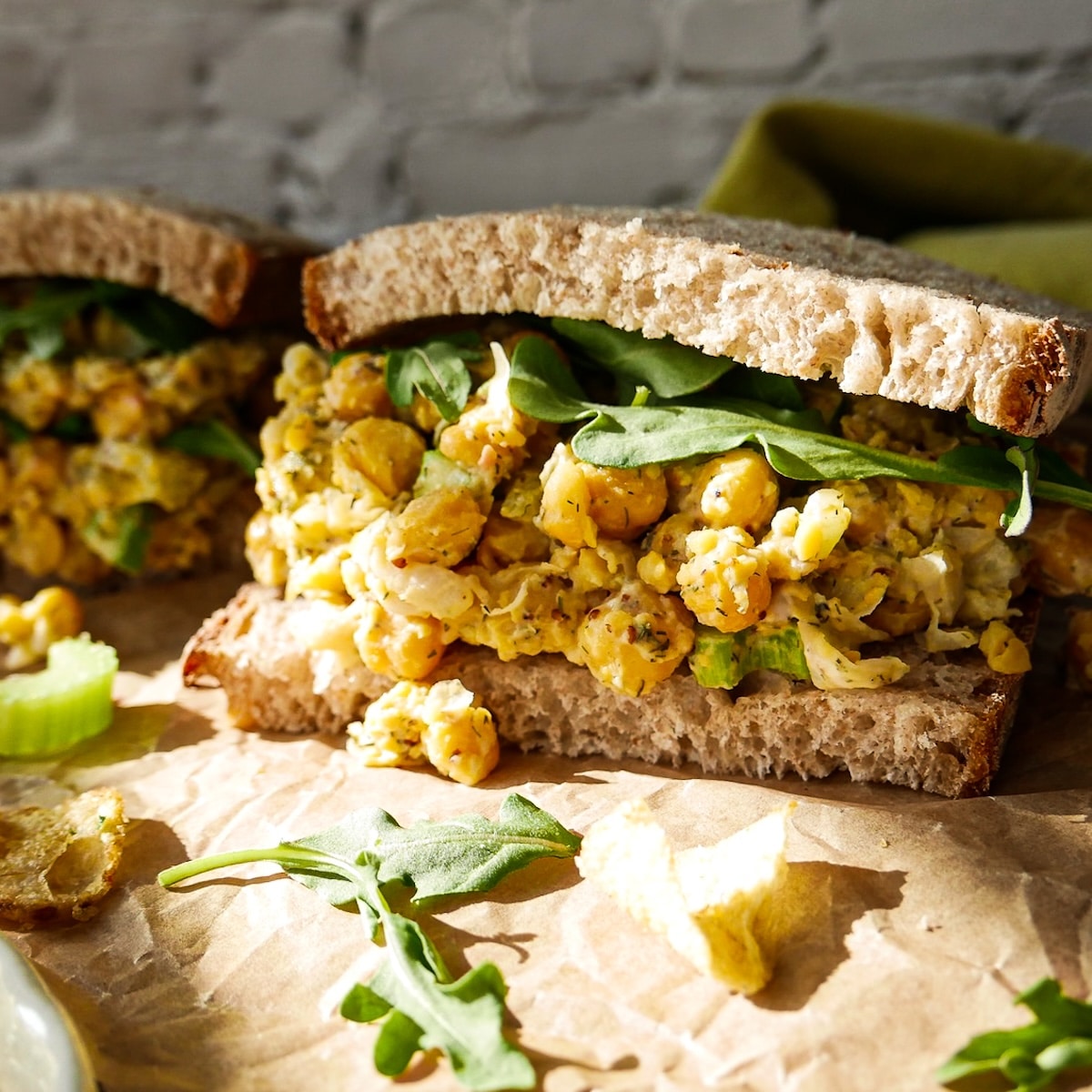 Chickpea egg salad sandwich topped with arugula. 