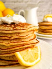 Stack of light lemon pancakes with fresh whipped cream.