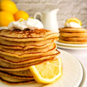 Stack of light lemon pancakes with fresh whipped cream.