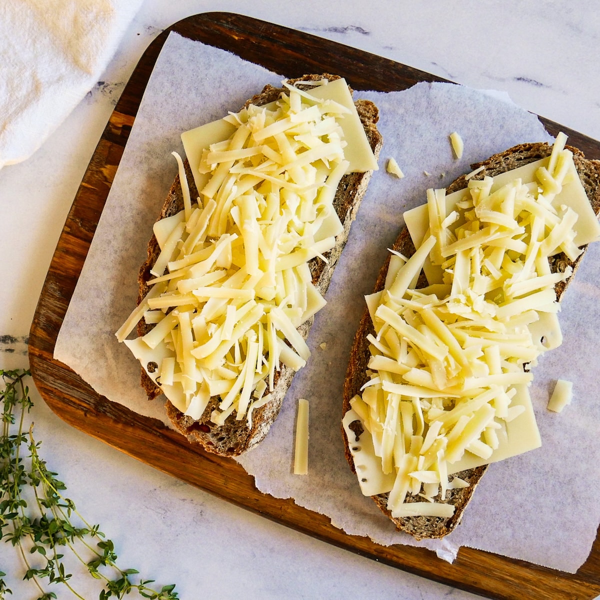 Two slices of sourdough bread in a skillet with cheese placed on top.