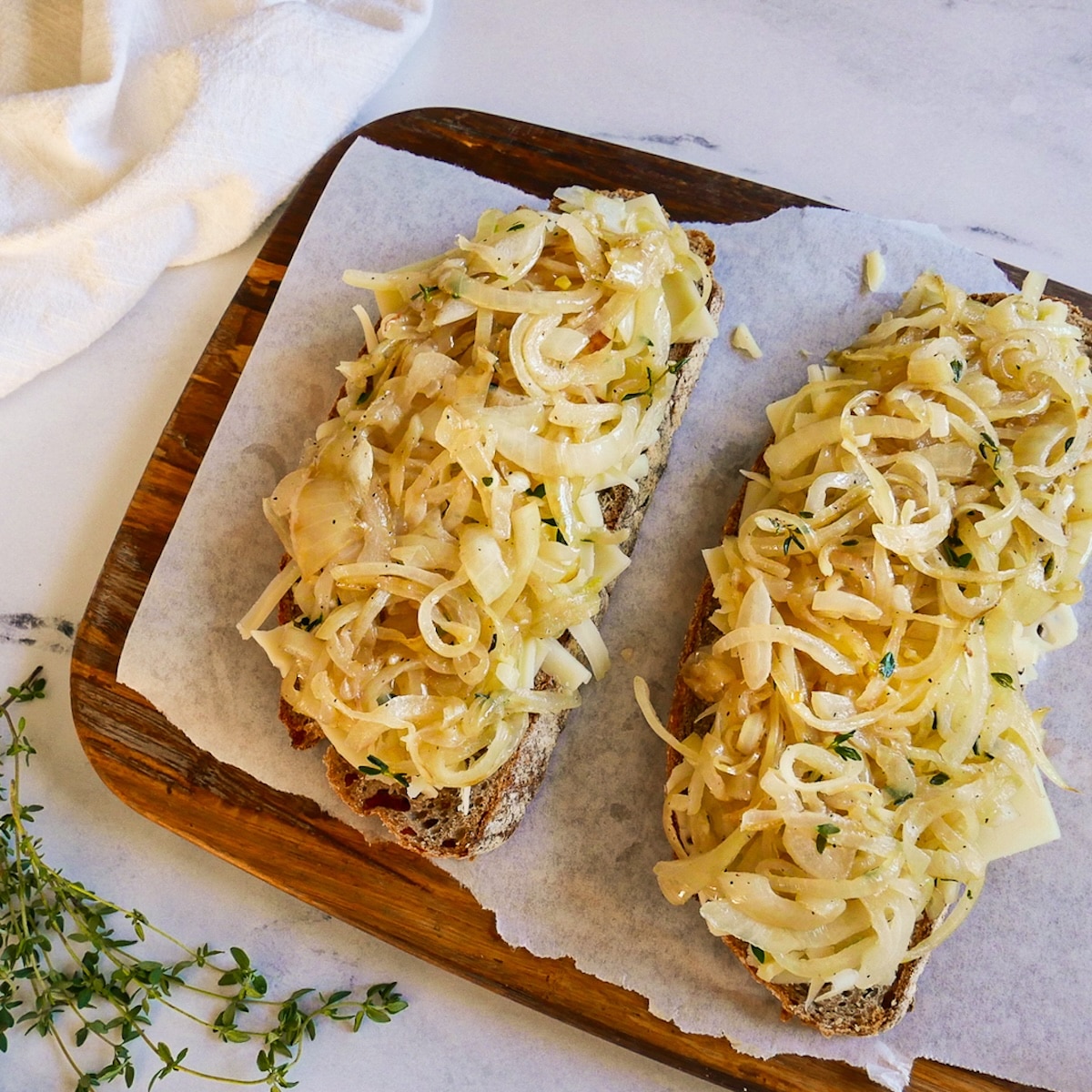 Caramelized onions and cheese placed on top of sourdough slices in a skillet.