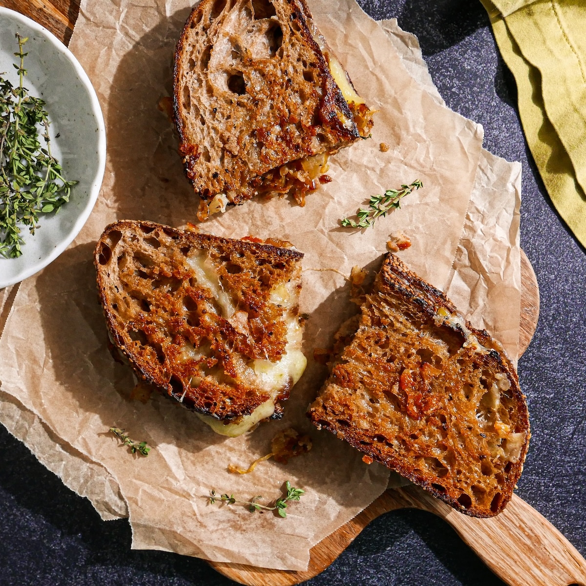 Sliced grilled cheese with caramelized onions on a cutting board.