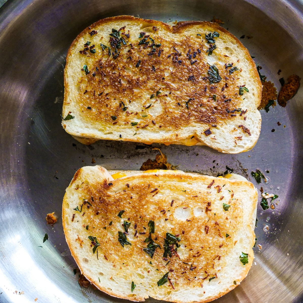grilled-cheese-in-skillet.jpg Grilled cheese being cooked until golden brown in a skillet.