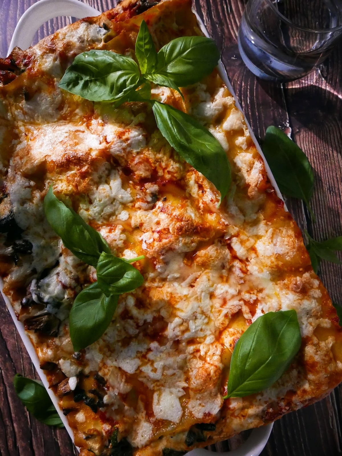 Pan of vegetable lasagna garnished with fresh basil.