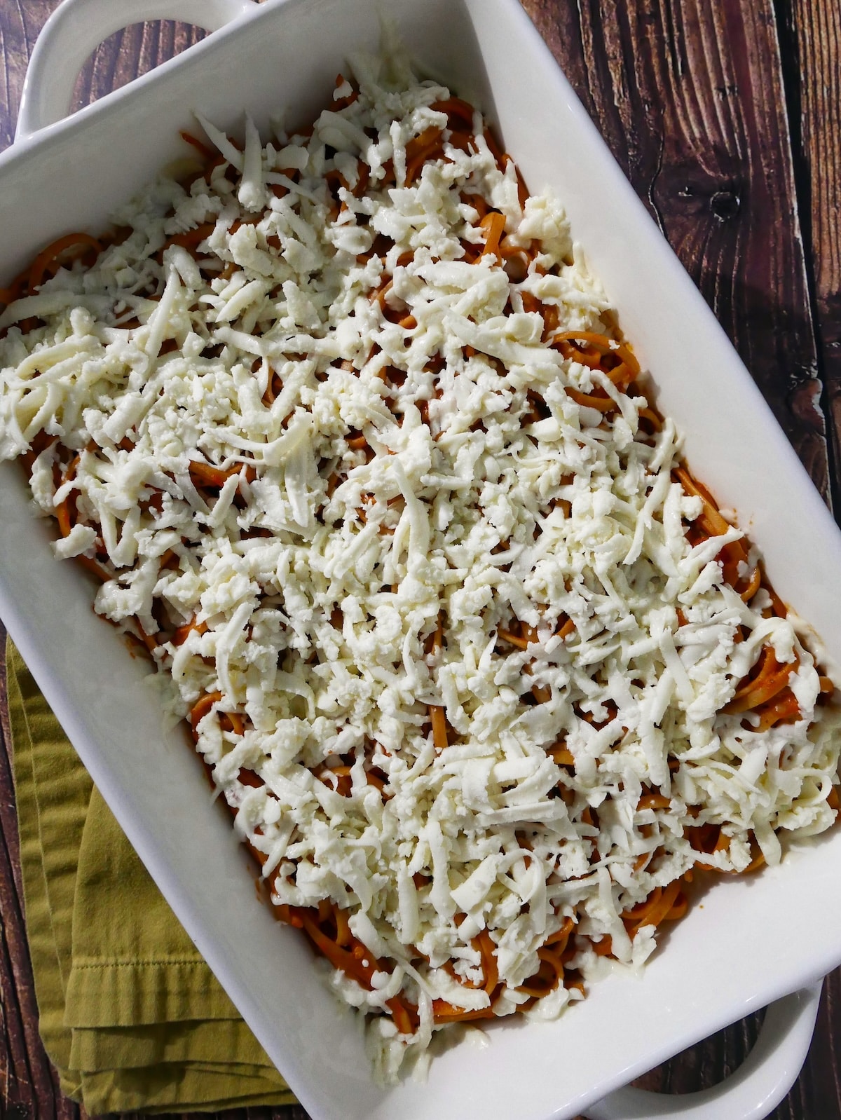 assembled-bake.jpg Grated mozzarella sprinkled on top of assembled leftover spaghetti.