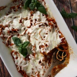 Baked leftover spaghetti in a baking dish with a large spoon.