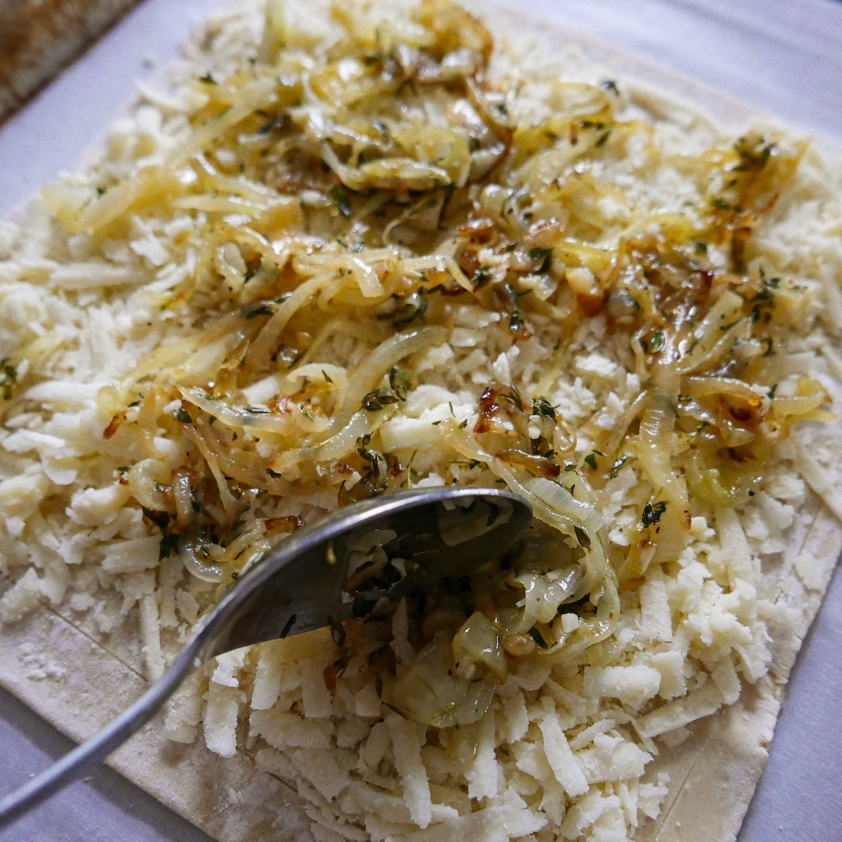 spooning-onions.jpg Spooning cooled onion mixture onto puff pastry.