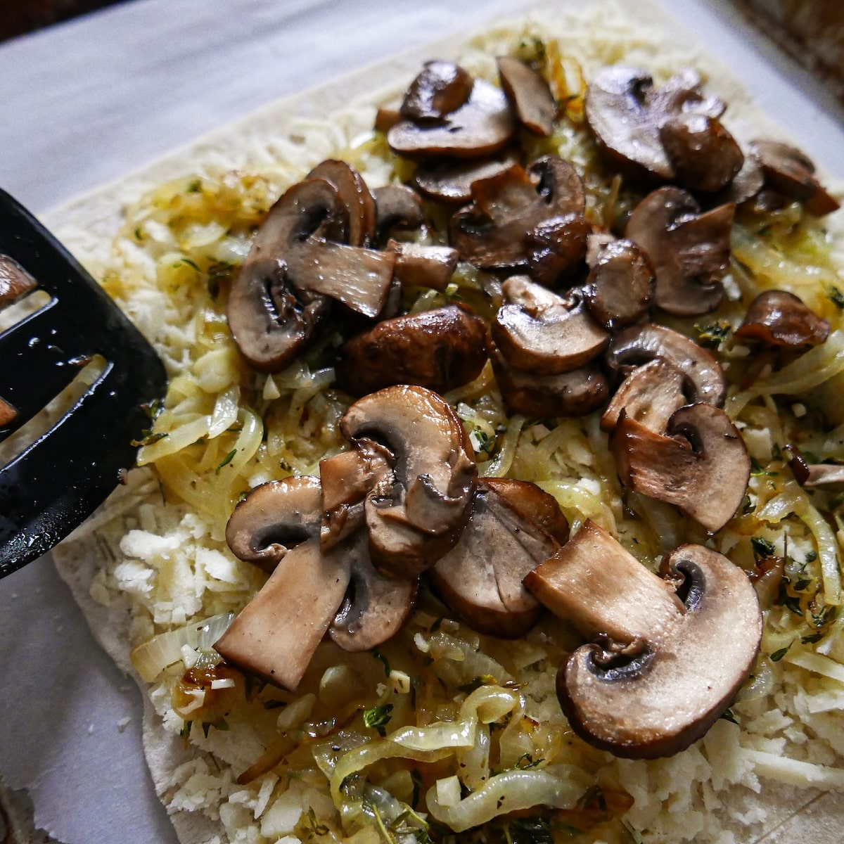 adding-mushrooms.jpg Adding browned mushrooms on top of tart.