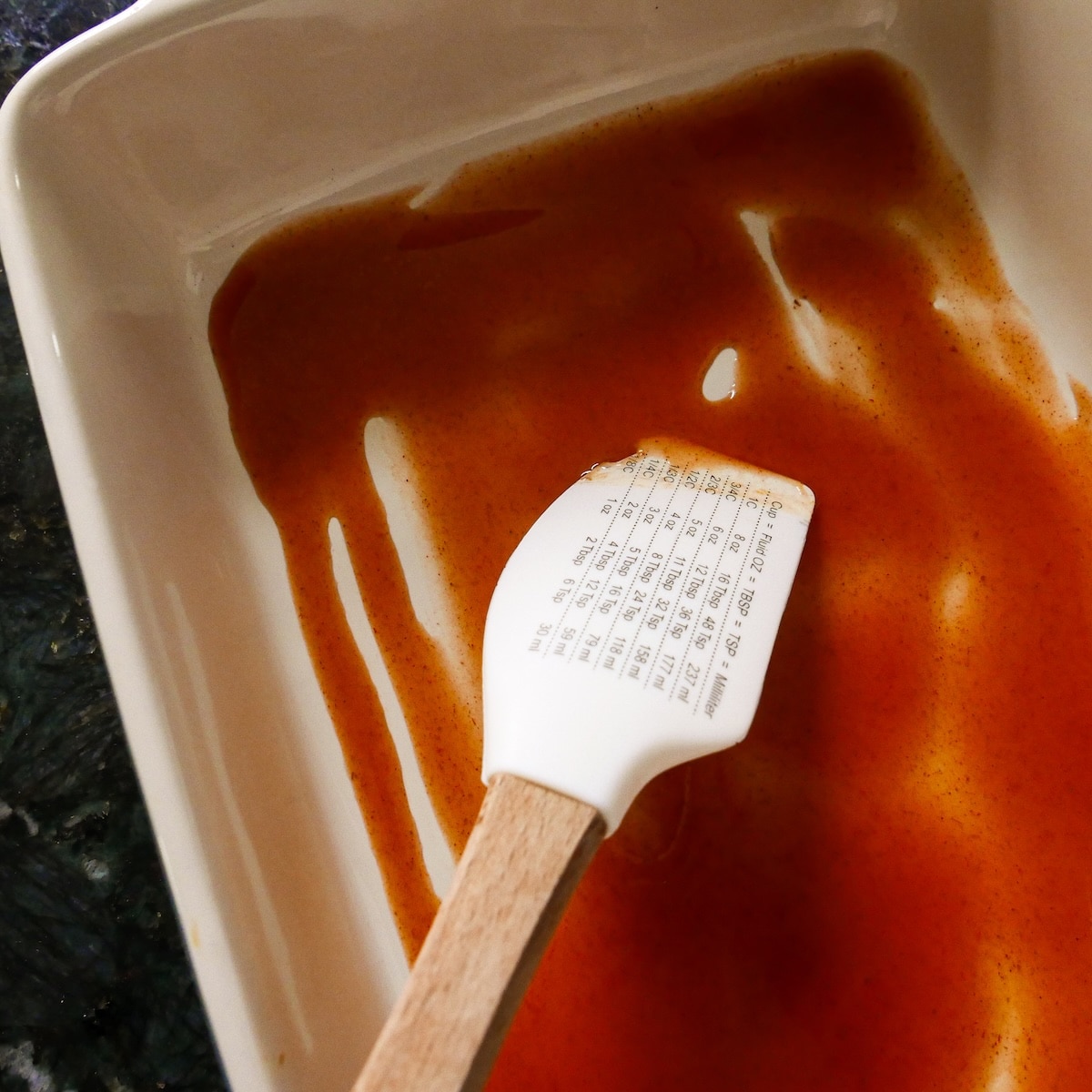 enchilada-sauce-in-pan.jpg Red enchilada sauce spread on the bottom of a baking dish.