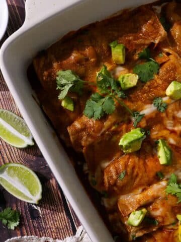 Sweet potato enchilada casserole in a baking dish with sliced limes.
