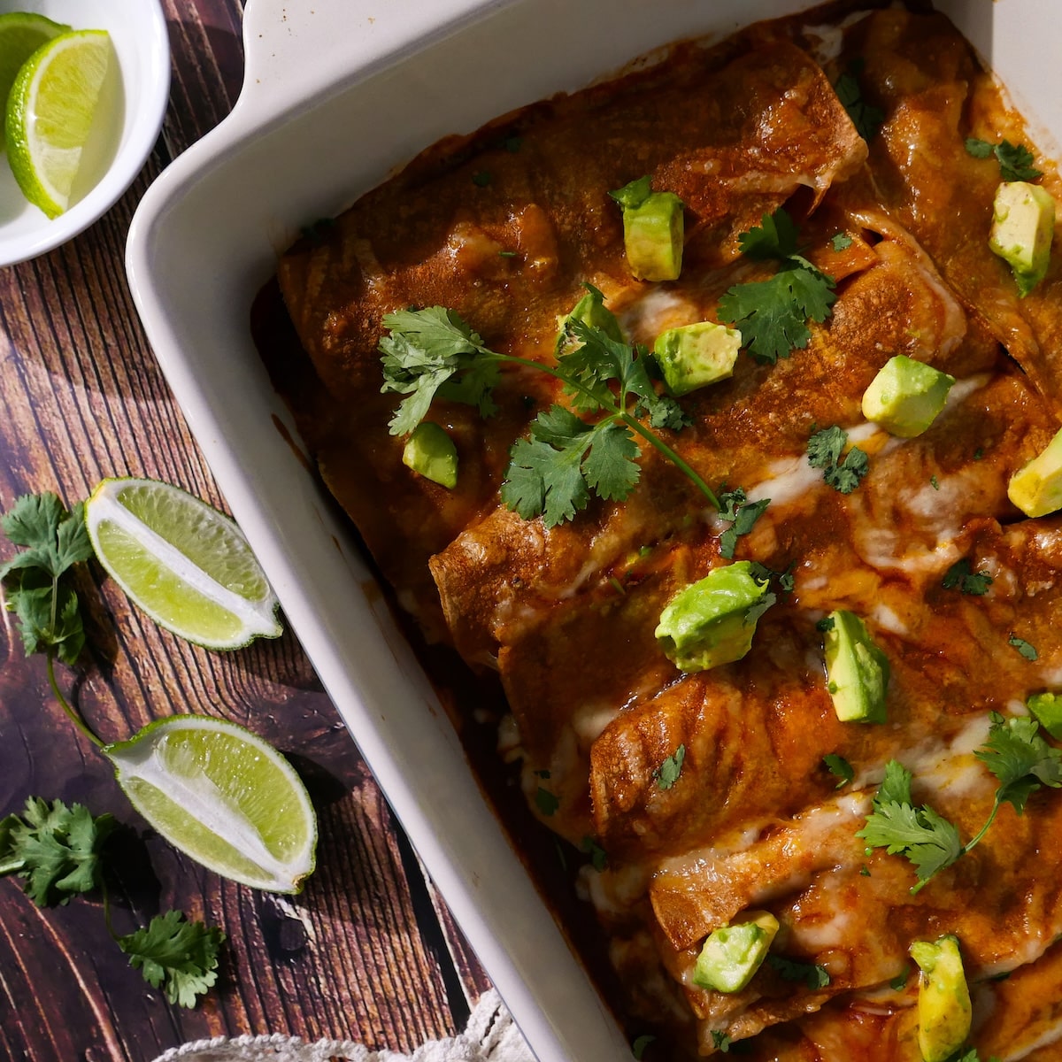 Sweet potato enchilada casserole in a baking dish with sliced limes.