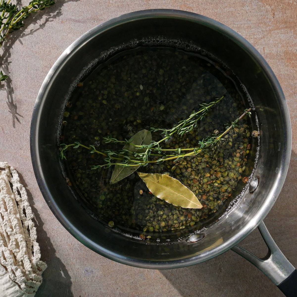 lentils-cooking.jpg Lentils in a pot of lightly salted water with thyme and by leaves.