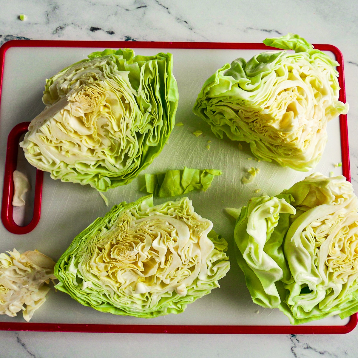 sliced-cabbage-wedges.jpg Four sliced cabbage wedges resting on a cutting board.