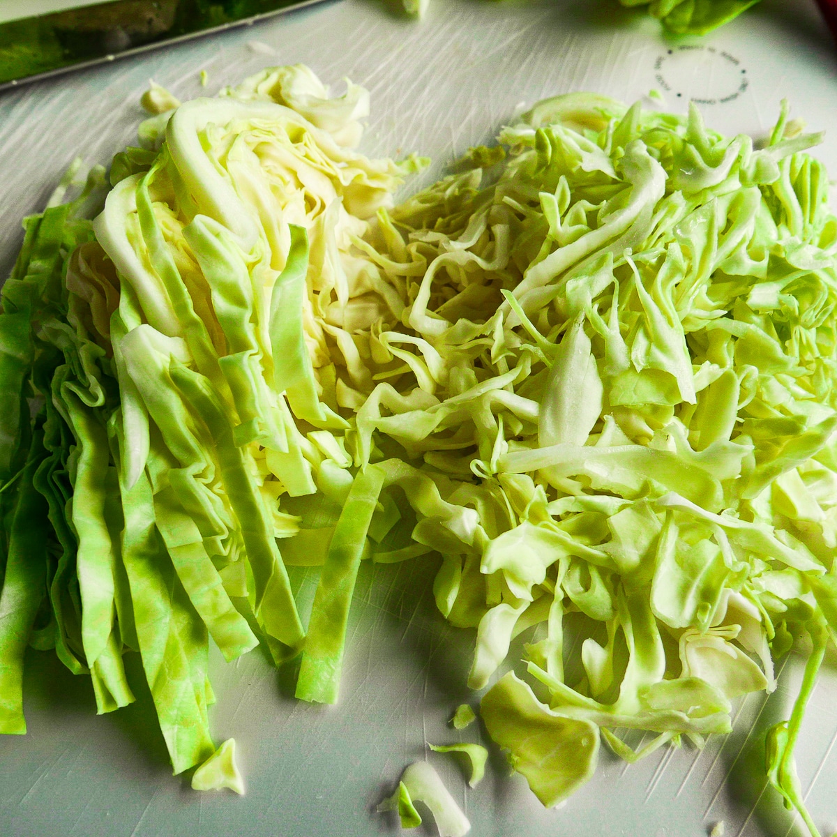 cut-cabbage.jpg Two piles of sliced green cabbage resting on a cutting board.