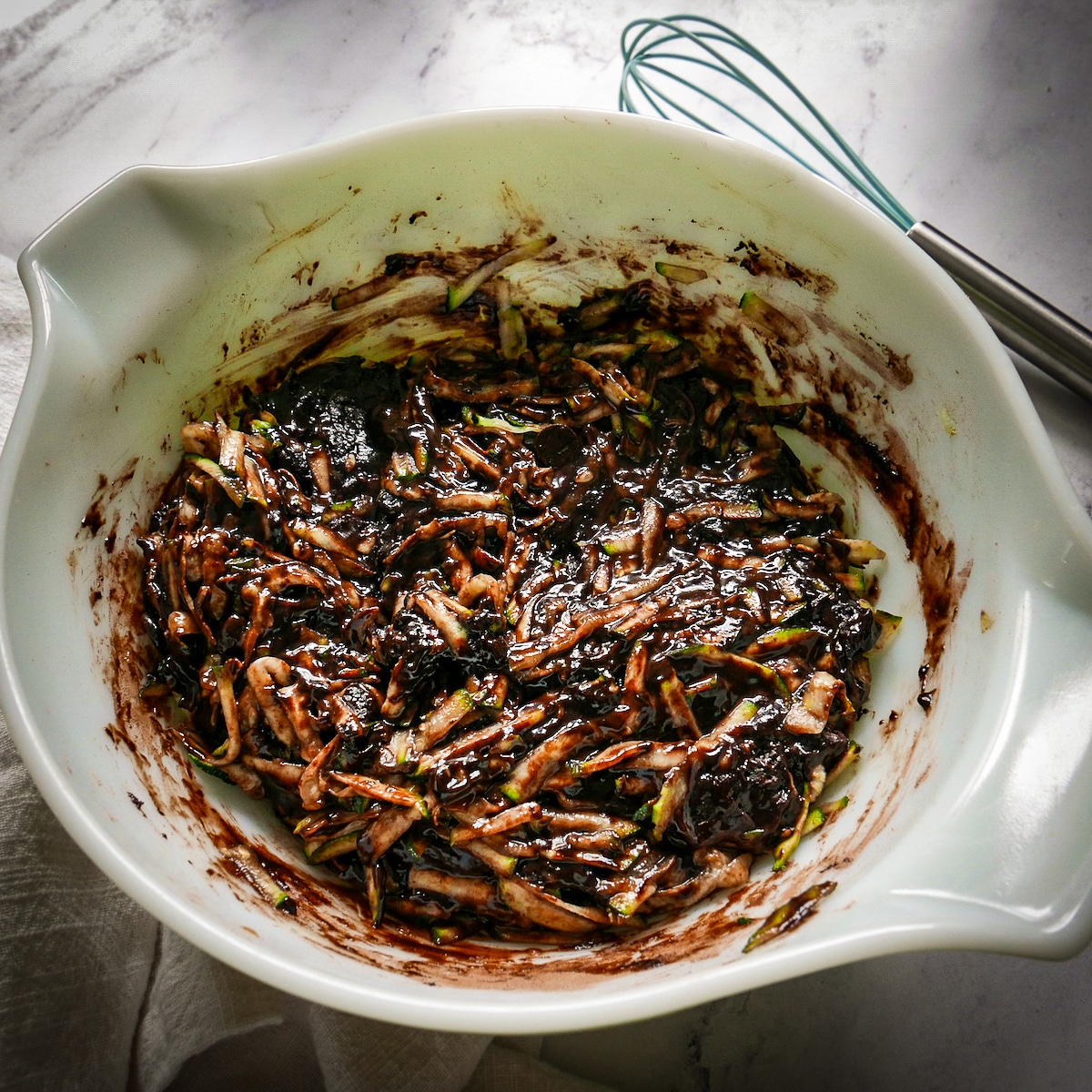 batter-in-bowl.jpg Wet and dry ingredients combined with zucchini in a bowl with a whisk in background.