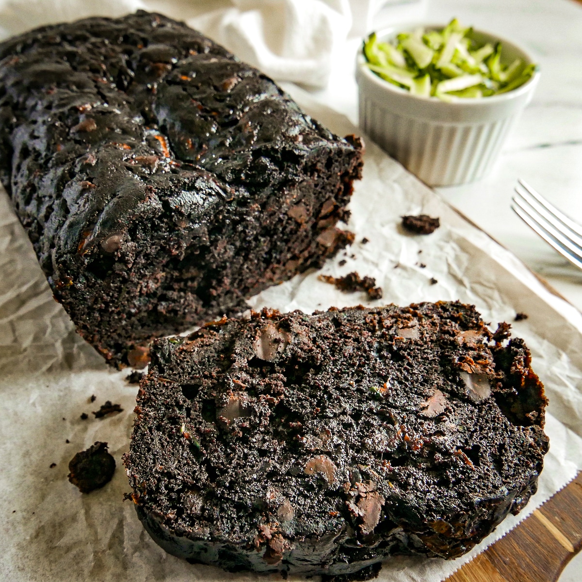 chocolate-zucchini-loaf.jpg Death by chocolate zucchini bread with one slice cut on a wooden board.