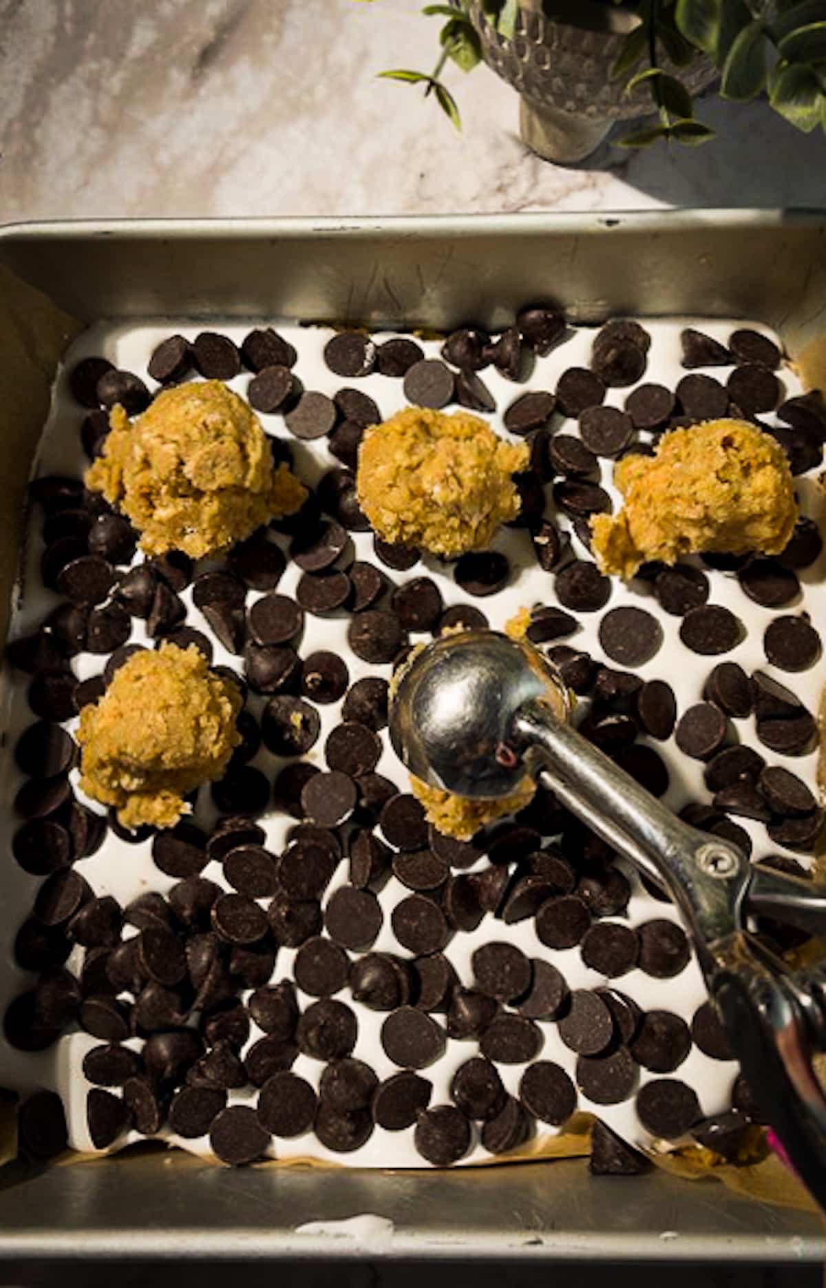 cookie-dough-on-bars.jpg Scooping graham cracker cookie dough on top of assembled cookie bars.