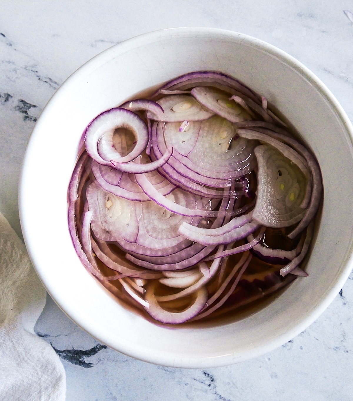 red-onion-in-liquid.jpg Thinly sliced red onion resting in pickling liquid.