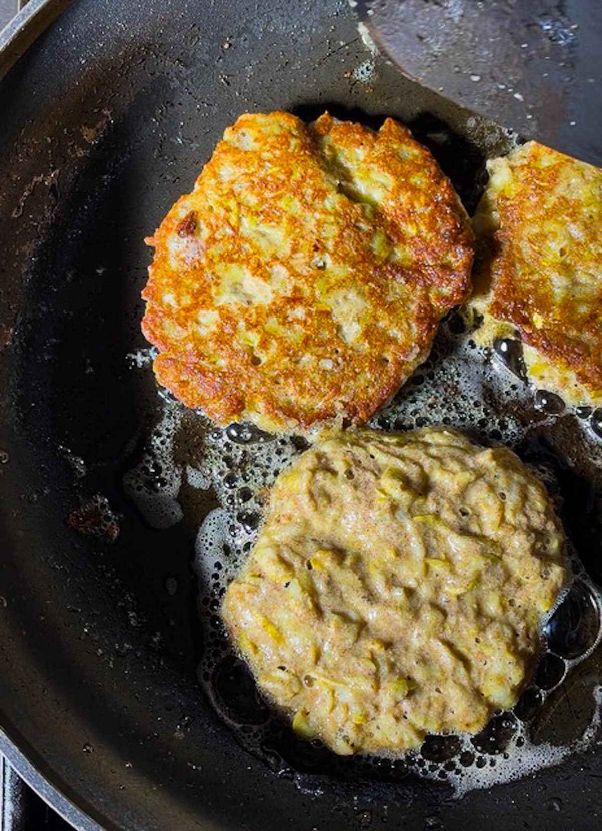 frying-fritters.jpg Frying zucchini fritters in a skillet with oil.