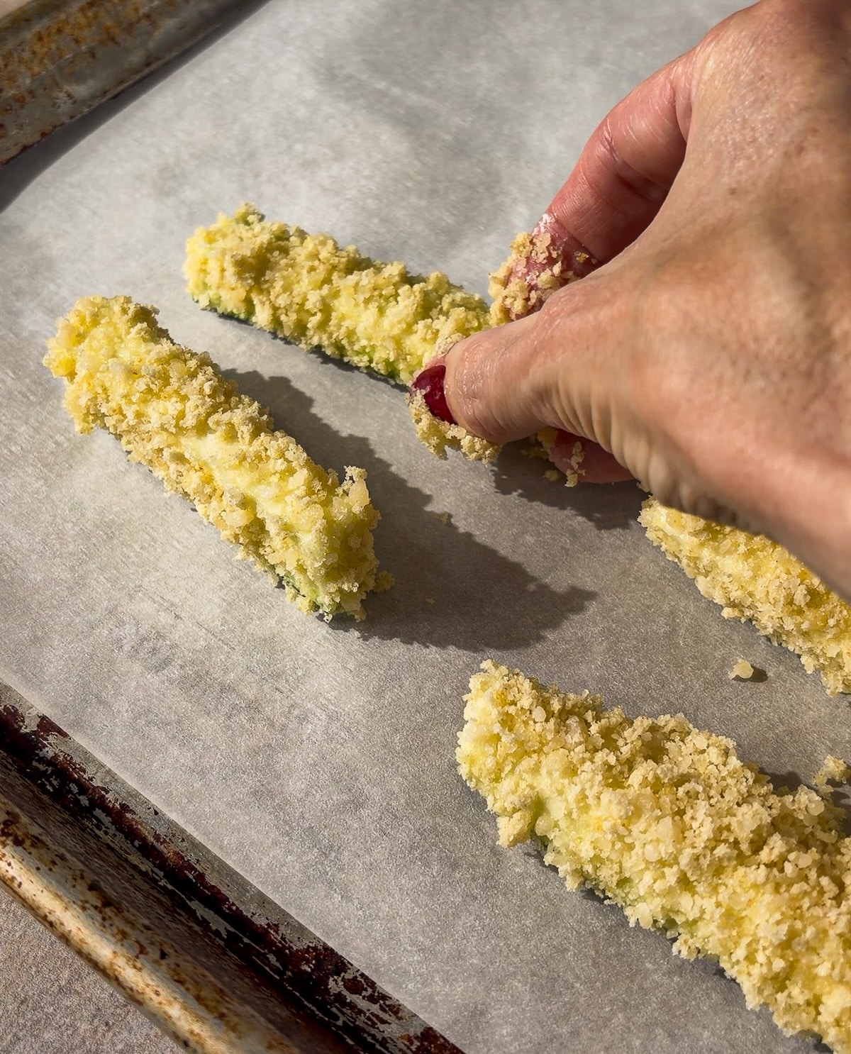breaded-zucchini-sticks.jpg Breaded zucchini sticks arranged on a baking sheet.