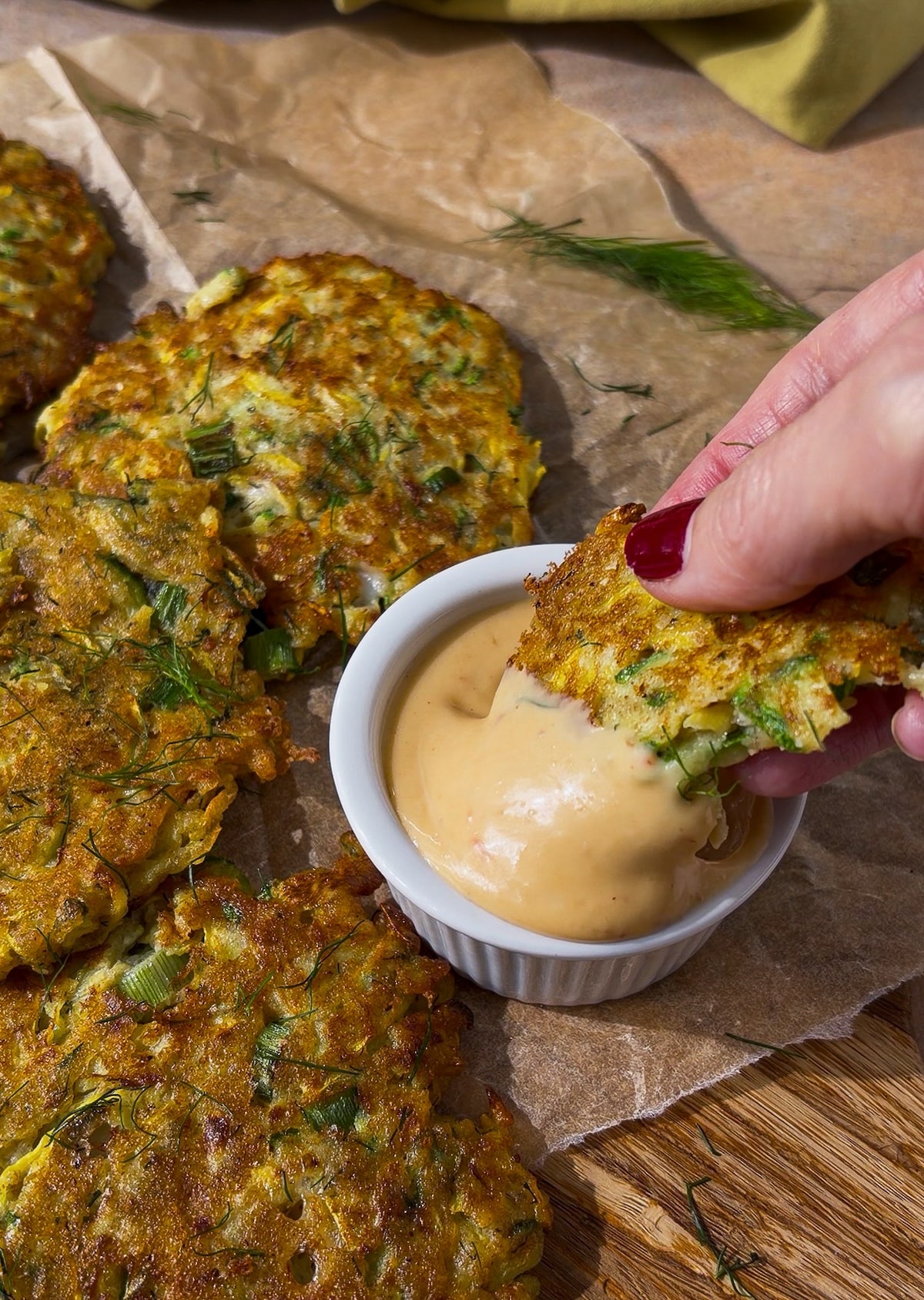 dipping-fritters.jpg dipping zucchini fritters with feta and dill into aioli.